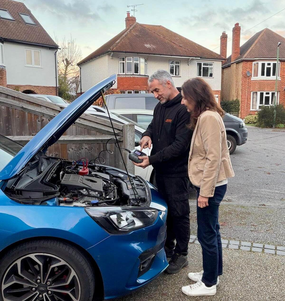 Explaining inspection results during a pre-purchase check Maxamy mobile mechanic showing diagnostic findings to a customer during a pre-purchase car inspection at their home.