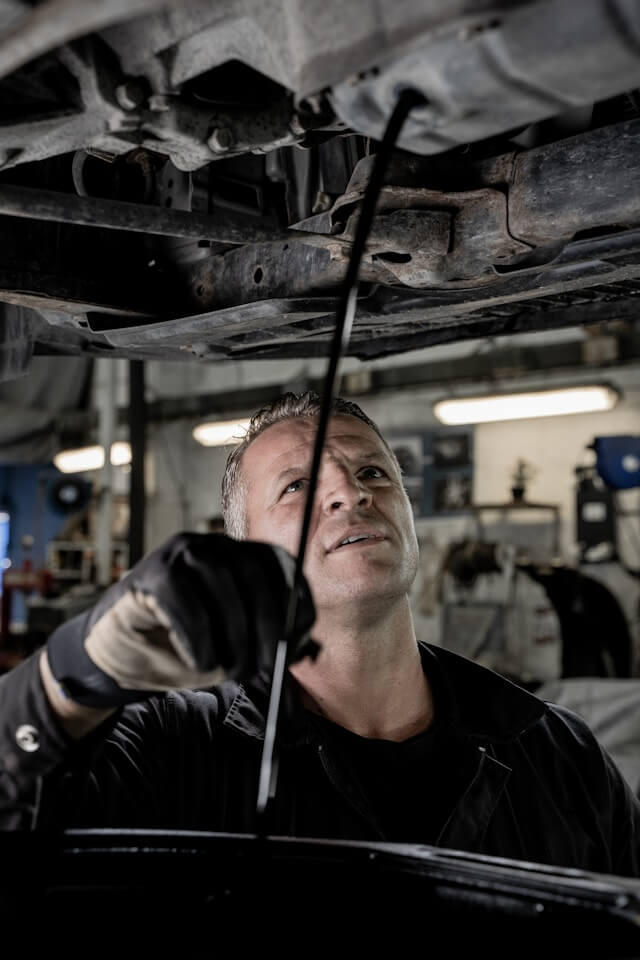 Experienced mobile mechanic inspecting underside of a vehicle in Maidenhead – Maxamy Autocare Mechanic inspecting the underside of a car in a garage, highlighting Maxamy’s mobile repair services in Maidenhead, Slough, and surrounding areas.