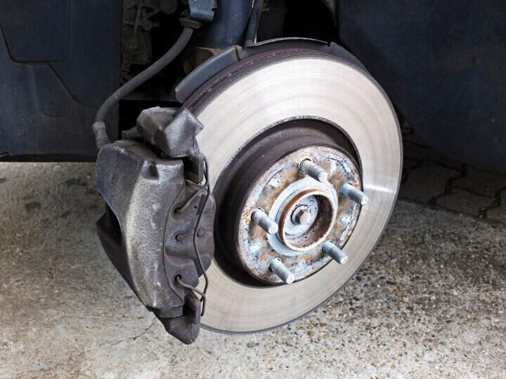 MOT Failure from Brake Wear and Damage Exposed car brake disc and caliper indicating brake system issues during MOT test