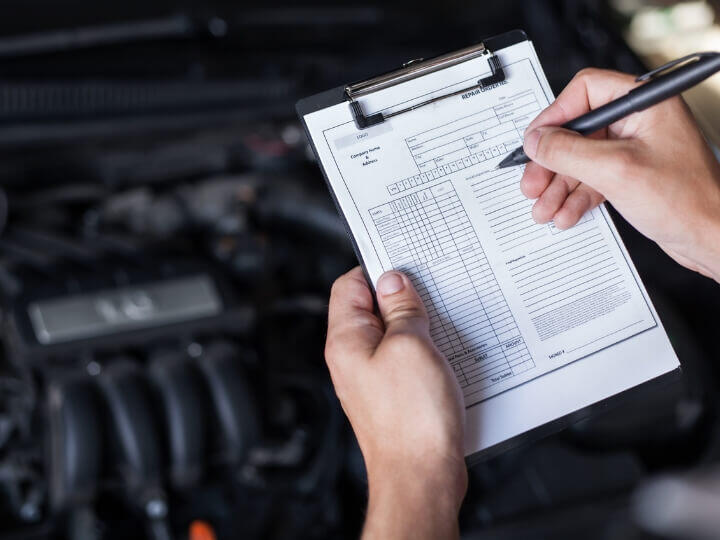 Mechanic Filling Out Inspection Form - Potential Service Scam Mechanic completing a vehicle inspection form, sometimes used to upsell unnecessary car services.